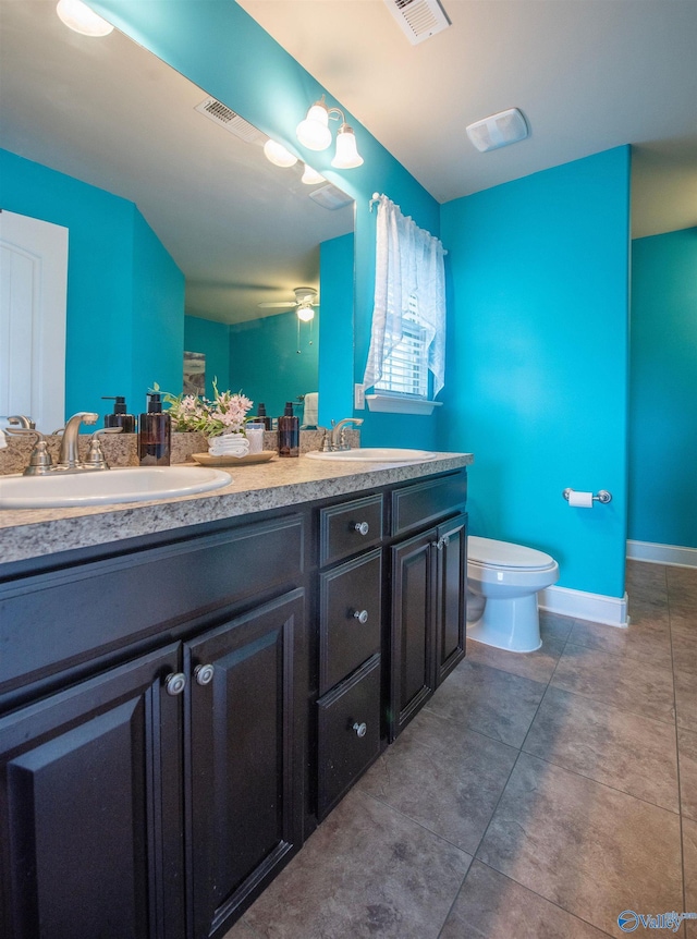 bathroom featuring double vanity, ceiling fan, visible vents, a sink, and toilet