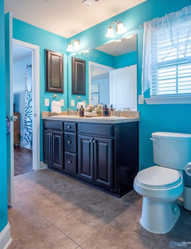 bathroom with double vanity, a sink, visible vents, and toilet