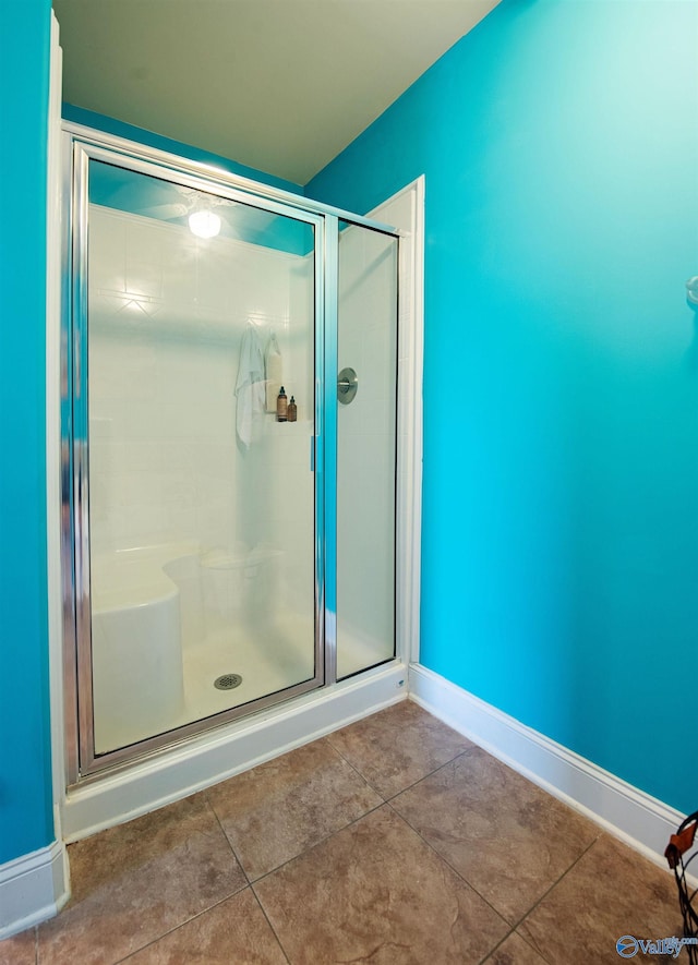 full bathroom featuring baseboards and a shower stall