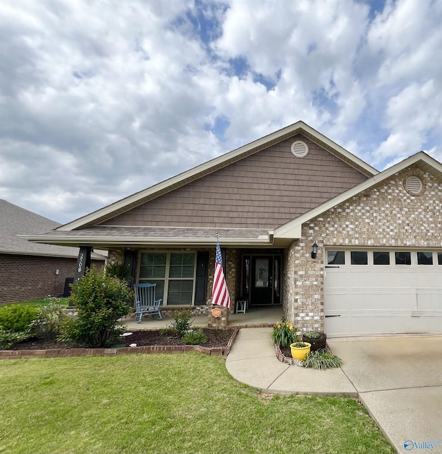 view of front of property featuring an attached garage, brick siding, a porch, a front yard, and driveway