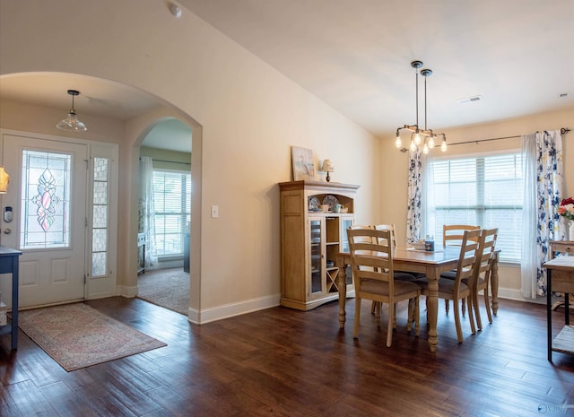 dining space with arched walkways, baseboards, plenty of natural light, and dark wood-type flooring