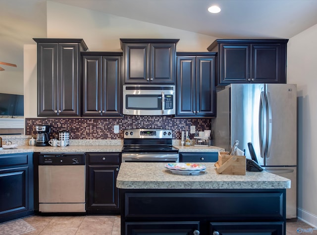 kitchen with light tile patterned flooring, light countertops, backsplash, vaulted ceiling, and stainless steel appliances