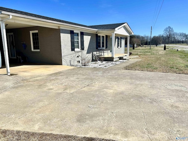 view of home's exterior featuring covered porch, driveway, an attached carport, and brick siding