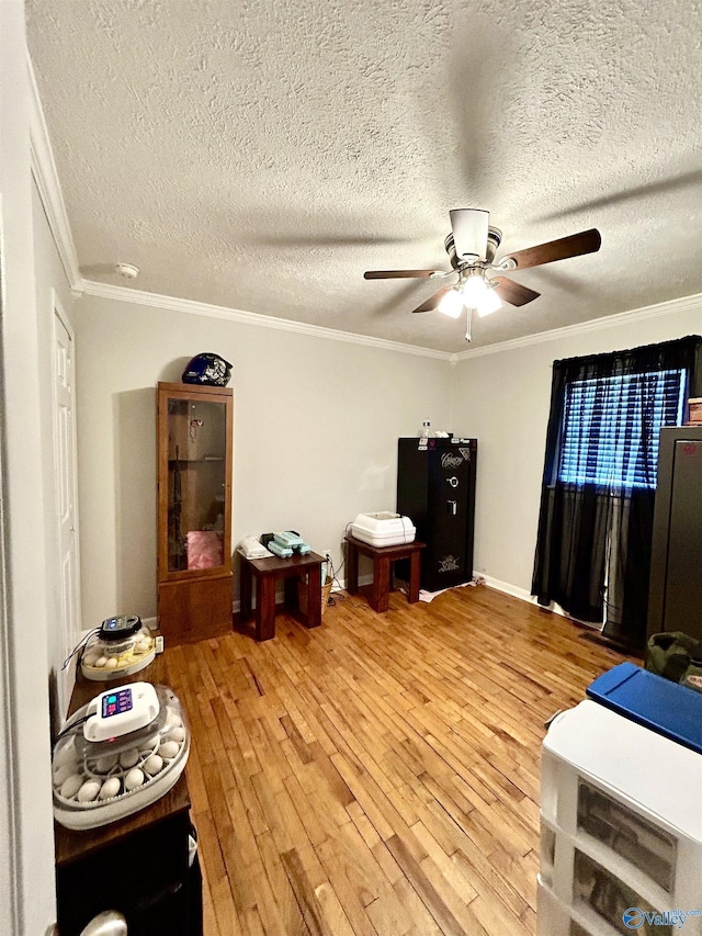 interior space with ceiling fan, ornamental molding, a textured ceiling, and wood finished floors