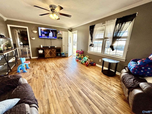 interior space featuring ornamental molding, a ceiling fan, a textured ceiling, wood finished floors, and baseboards