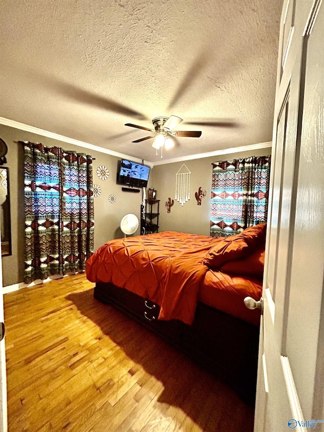 bedroom featuring crown molding, a textured ceiling, ceiling fan, and wood finished floors