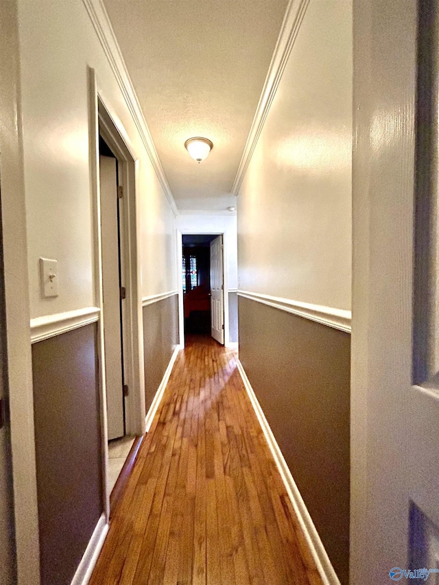 corridor featuring ornamental molding, wood finished floors, and baseboards