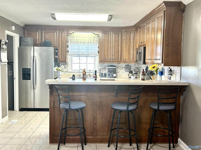 kitchen with decorative backsplash, a kitchen breakfast bar, a peninsula, stainless steel appliances, and light countertops