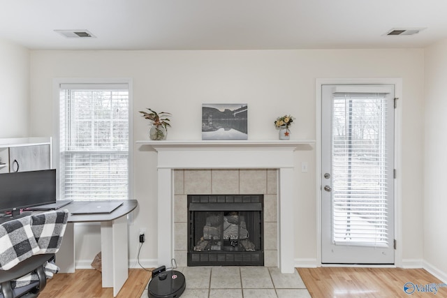 living room with a tiled fireplace and light hardwood / wood-style flooring