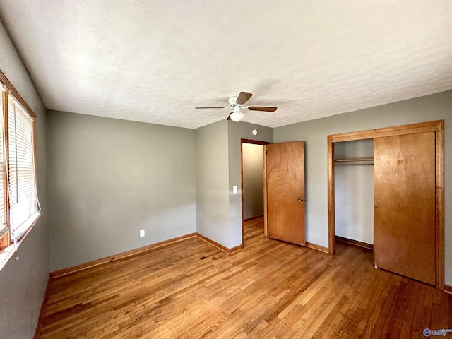 unfurnished bedroom with light wood finished floors, a textured ceiling, baseboards, and a closet