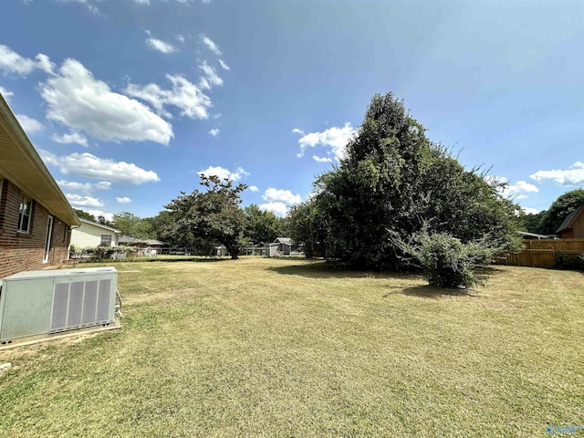 view of yard with central AC and fence