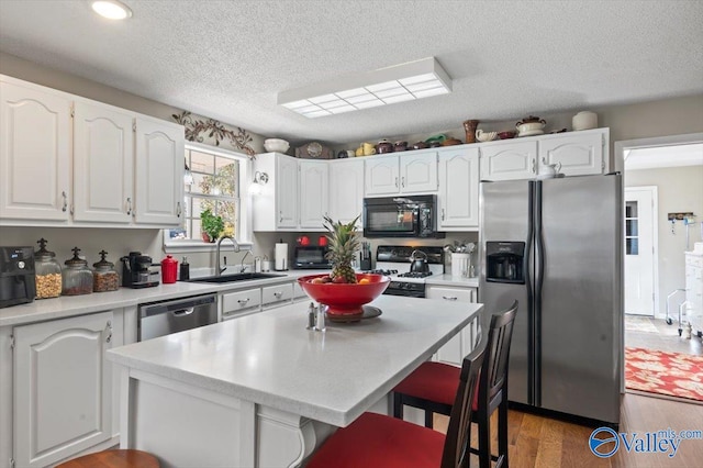 kitchen with sink, white cabinets, black appliances, and dark hardwood / wood-style floors