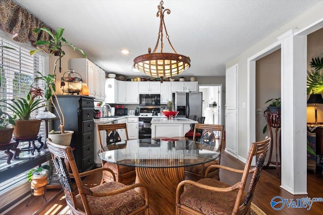 dining space with a textured ceiling, dark wood-type flooring, and sink