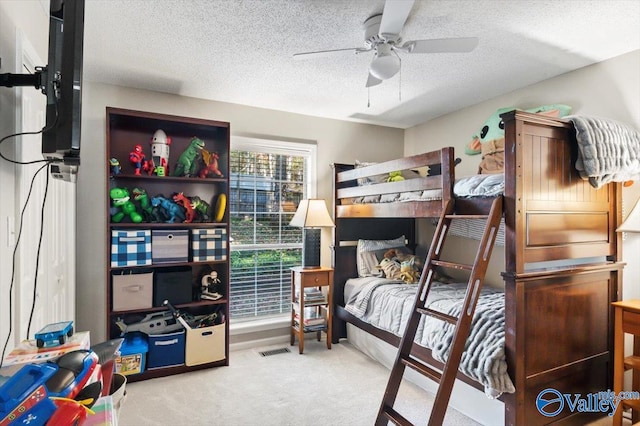 bedroom with ceiling fan, light colored carpet, and a textured ceiling