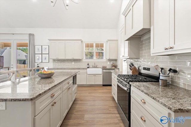 kitchen with white cabinets, sink, light stone countertops, and stainless steel appliances