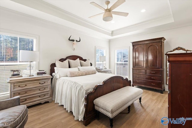 bedroom with a raised ceiling, ceiling fan, light hardwood / wood-style flooring, and crown molding