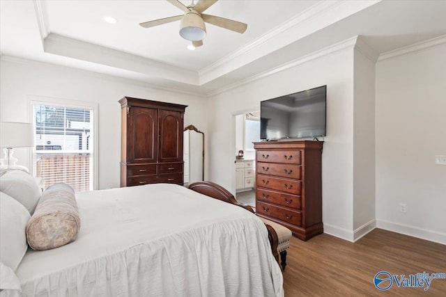 bedroom featuring crown molding, ensuite bath, ceiling fan, a tray ceiling, and dark hardwood / wood-style flooring