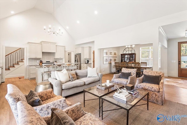 living room featuring light hardwood / wood-style flooring, high vaulted ceiling, and a notable chandelier