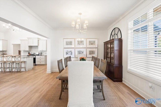 dining room featuring crown molding, light wood-type flooring, and an inviting chandelier