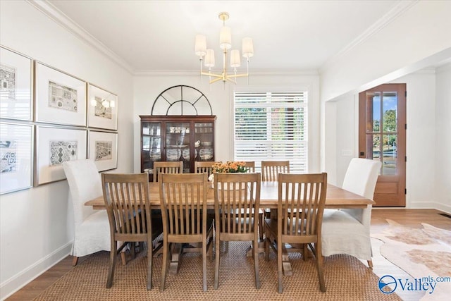 dining room with hardwood / wood-style floors, crown molding, and an inviting chandelier