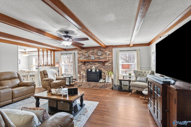 living area with a textured ceiling, beamed ceiling, wood finished floors, and a ceiling fan