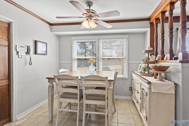 dining space featuring a textured ceiling, ceiling fan, light tile patterned flooring, baseboards, and ornamental molding