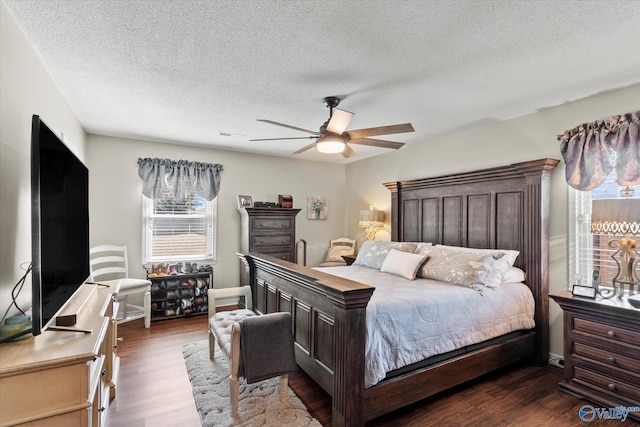 bedroom with ceiling fan, a textured ceiling, baseboards, and dark wood-type flooring