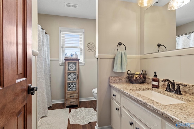 bathroom with toilet, wood finished floors, vanity, visible vents, and baseboards