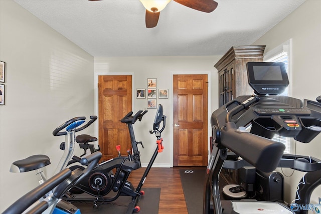 exercise area featuring dark wood-type flooring, ceiling fan, a textured ceiling, and baseboards