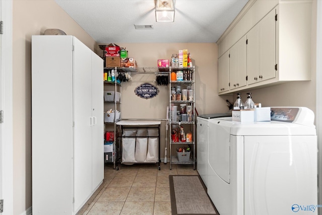 laundry area featuring cabinet space, light tile patterned floors, visible vents, and washing machine and clothes dryer