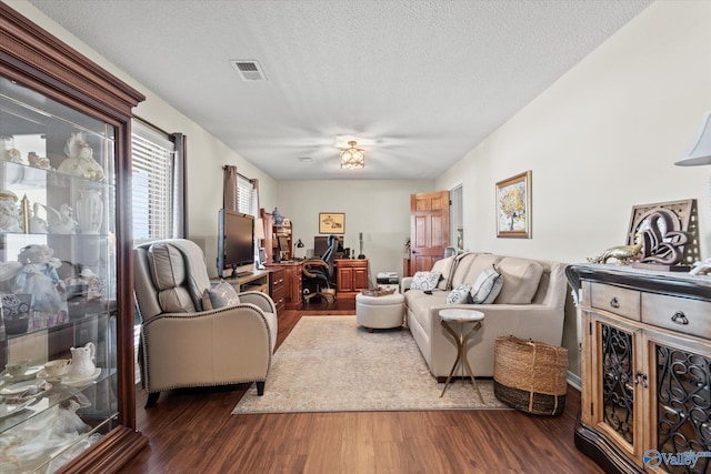 living room with visible vents, dark wood finished floors, and a textured ceiling