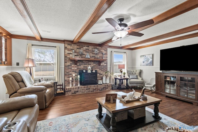 living room with a textured ceiling, ceiling fan, dark wood finished floors, and beam ceiling