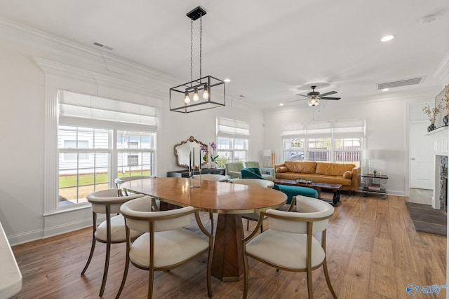 dining area with ceiling fan with notable chandelier, crown molding, and hardwood / wood-style floors