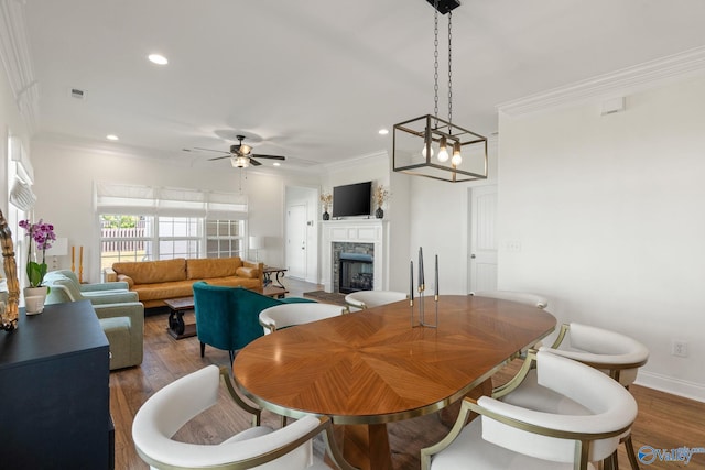 dining room featuring ceiling fan with notable chandelier, wood-type flooring, and ornamental molding