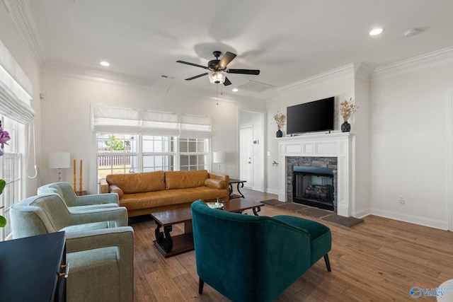 living room with dark hardwood / wood-style floors, crown molding, ceiling fan, and a stone fireplace