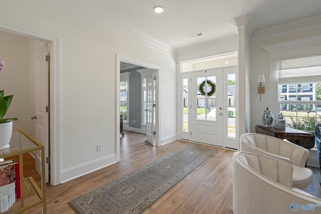 entryway with ornamental molding, a wealth of natural light, ornate columns, and light hardwood / wood-style floors