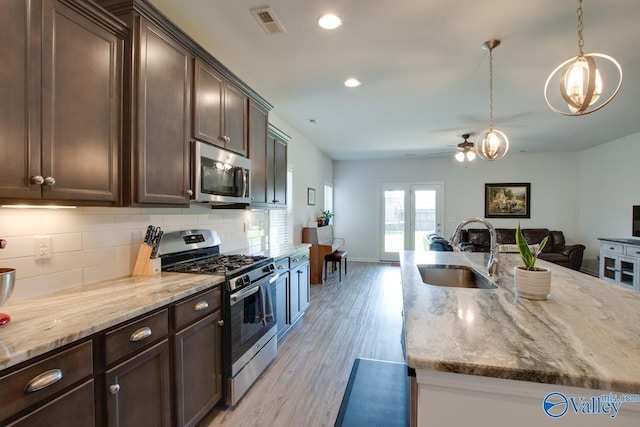 4304 Adventura Dr, Owens Cross Roads, AL 35763 - kitchen with appliances with stainless steel finishes, a sink, dark brown cabinetry, decorative backsplash, and light stone counters