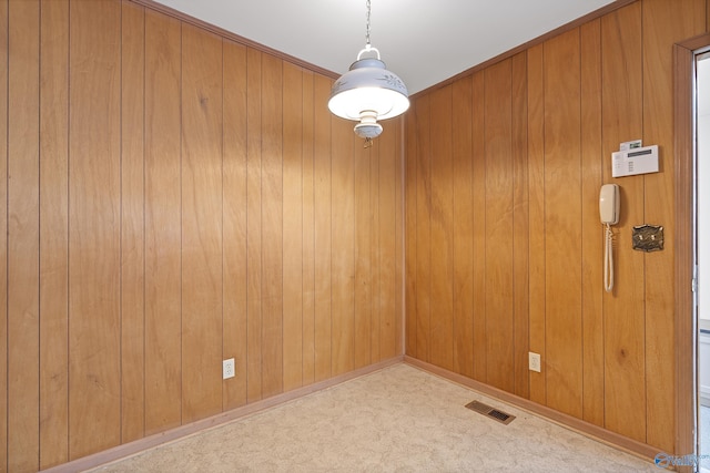 unfurnished dining area with wooden walls, visible vents, and carpet flooring