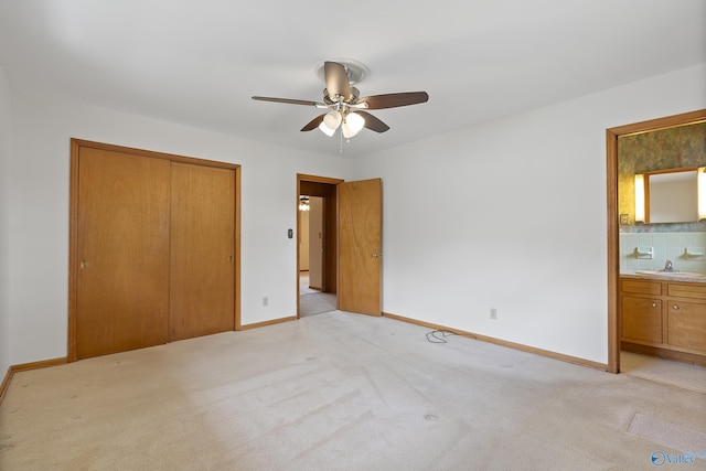 unfurnished bedroom featuring ensuite bath, baseboards, light carpet, and a closet