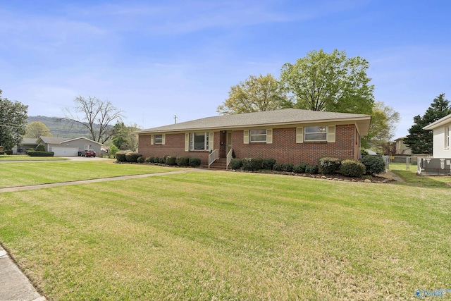 single story home with brick siding, central air condition unit, a front yard, and fence