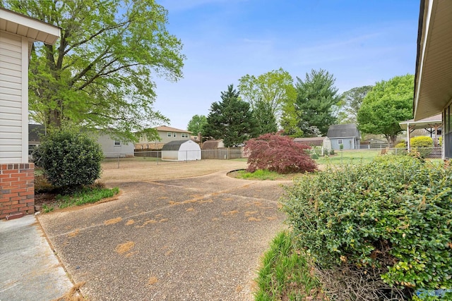 view of yard with a storage shed, fence, and an outdoor structure