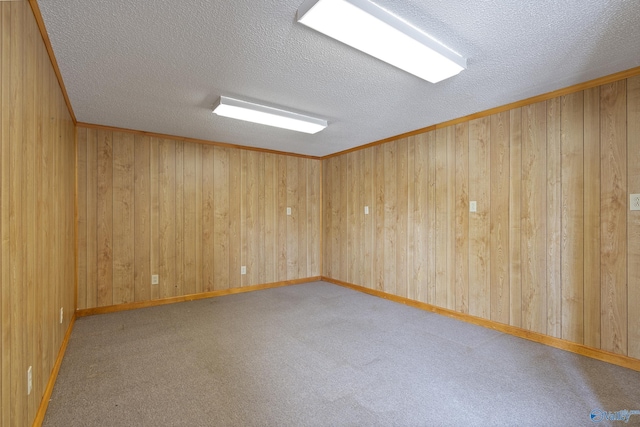 carpeted empty room featuring a textured ceiling and wooden walls