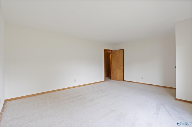 unfurnished room featuring baseboards and light carpet