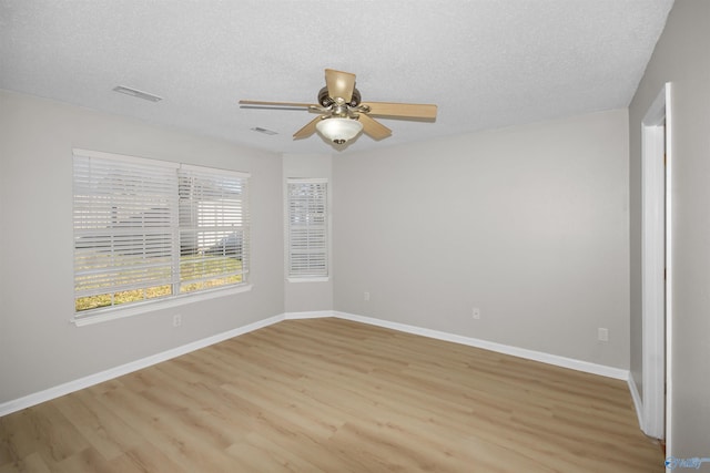 unfurnished room featuring baseboards, visible vents, light wood-style flooring, and a textured ceiling