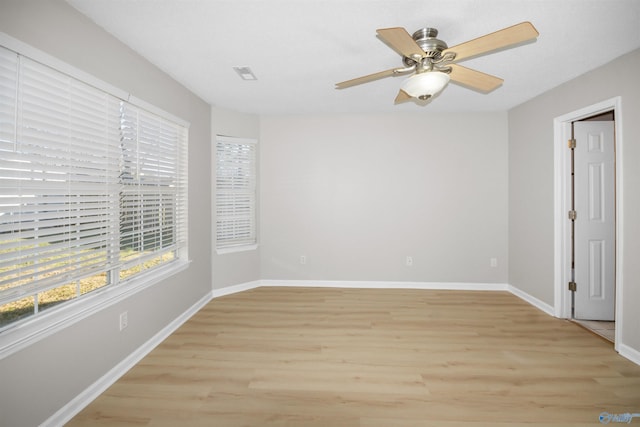 empty room with a ceiling fan, baseboards, visible vents, and light wood finished floors