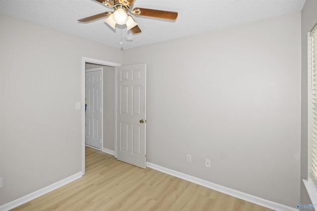 empty room with ceiling fan, a textured ceiling, baseboards, and wood finished floors