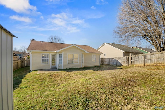 back of house with a fenced backyard, a patio, and a yard