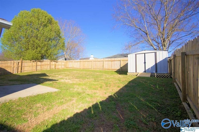 view of yard with a fenced backyard, a storage unit, and an outbuilding