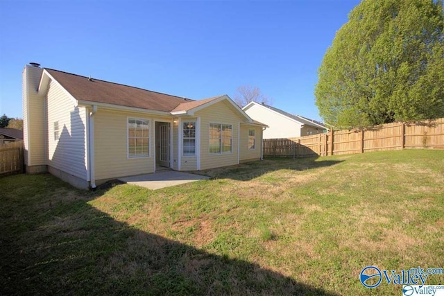 back of house featuring a fenced backyard, a yard, and a chimney