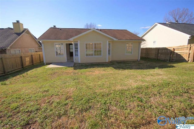 rear view of house with a fenced backyard and a lawn